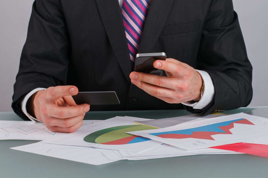 Businessman holding business card and smartphone.