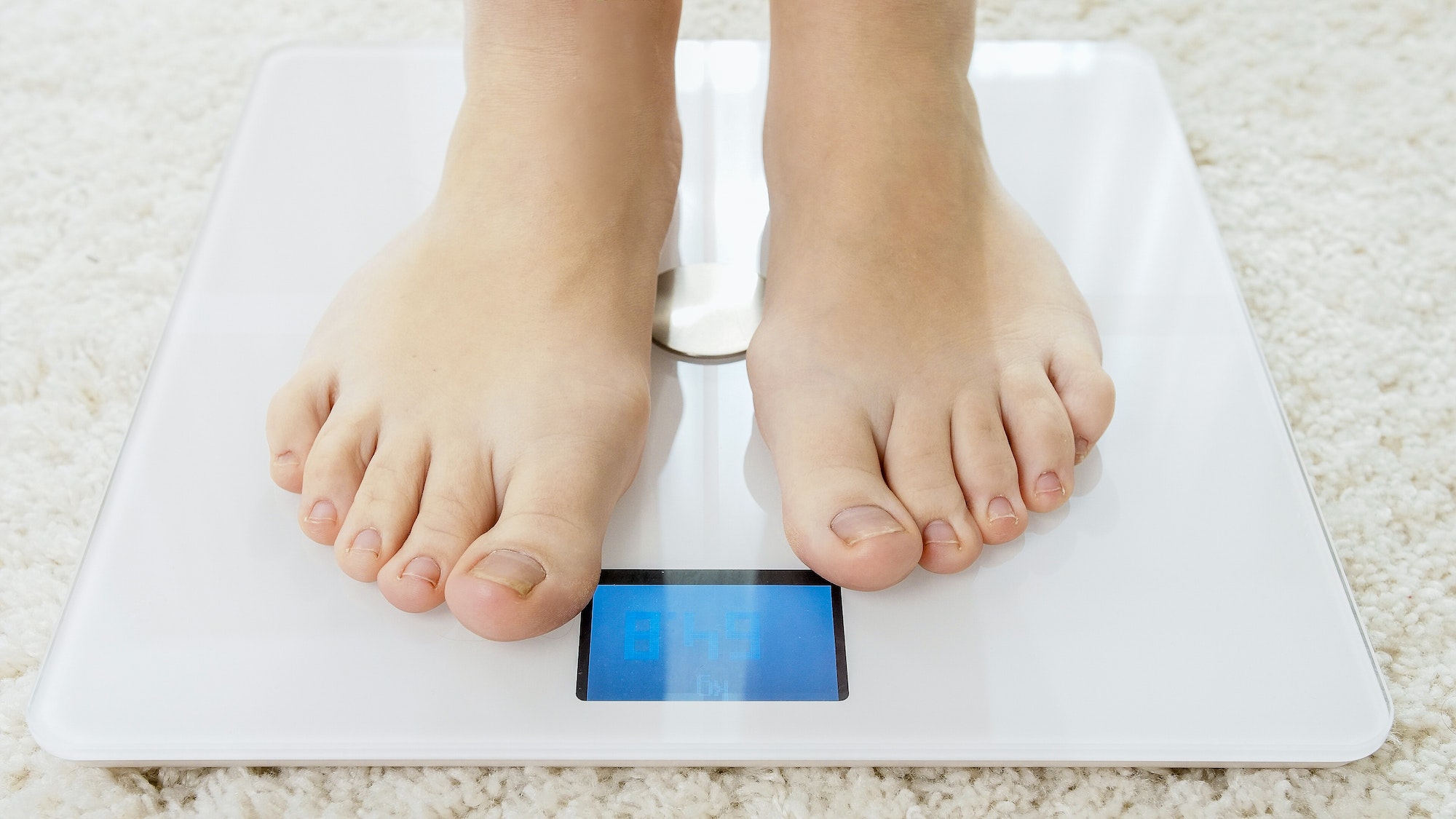 Closeup of barefoot woman using digital scales and checking her weight. Concept of dieting, loosing